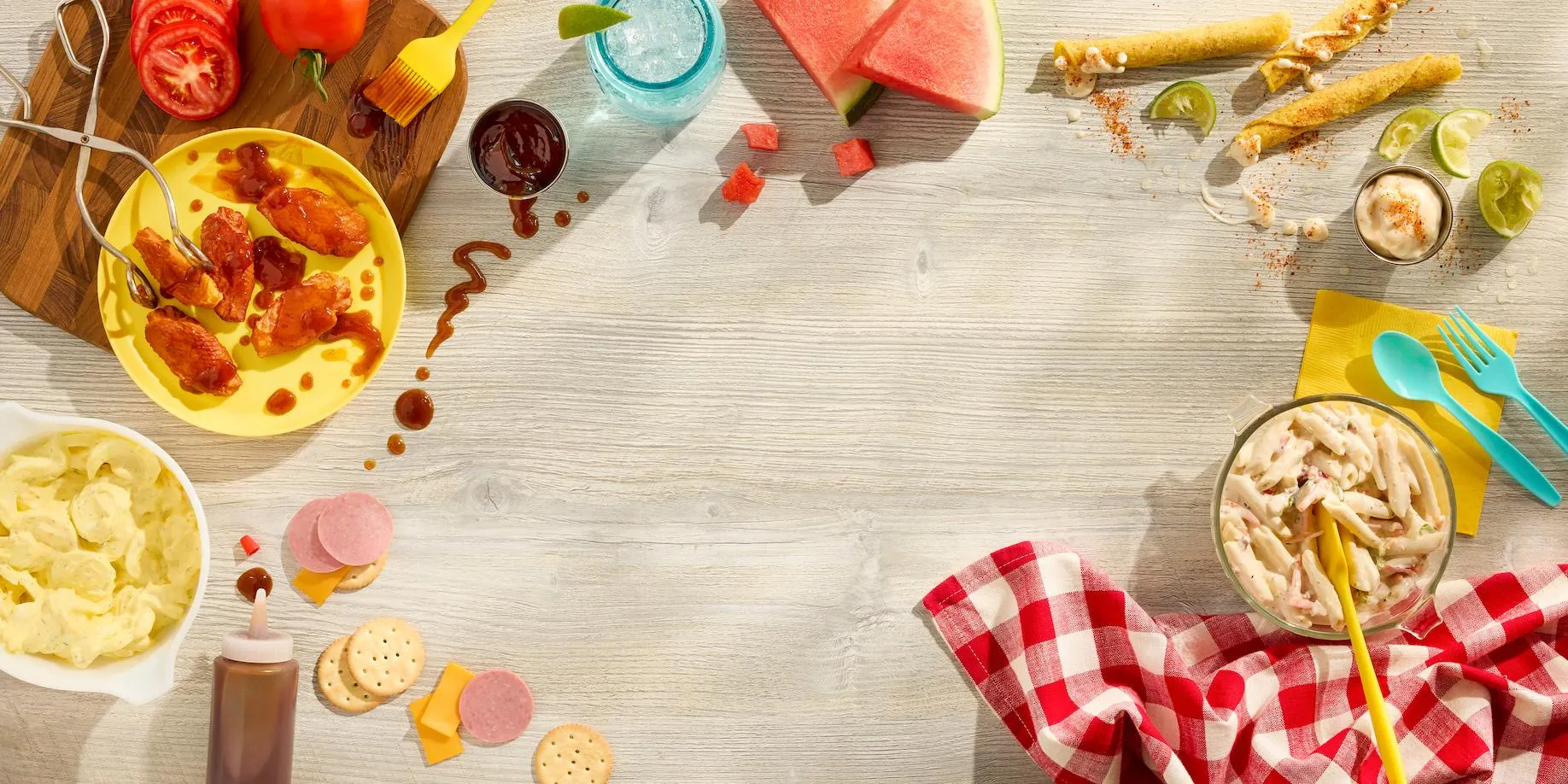 Picnic spread of snacks framing an empty wooden tabletop
