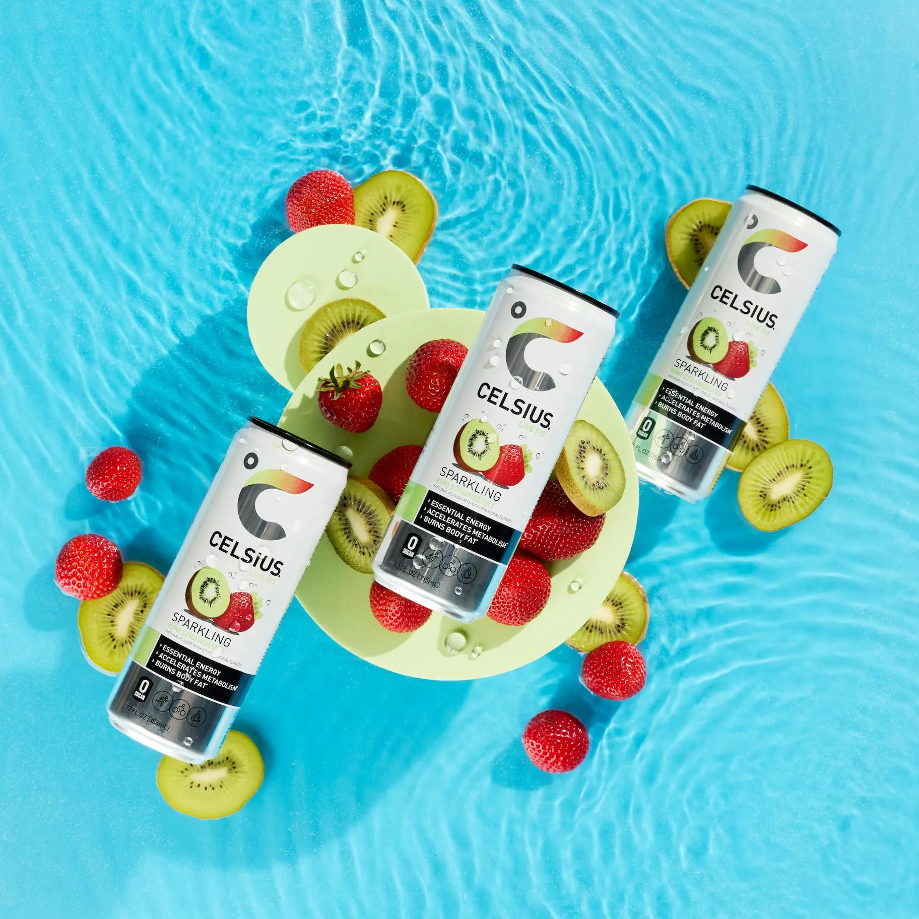 Celsius cans on a lily pad float in a pool with strawberries and kiwi