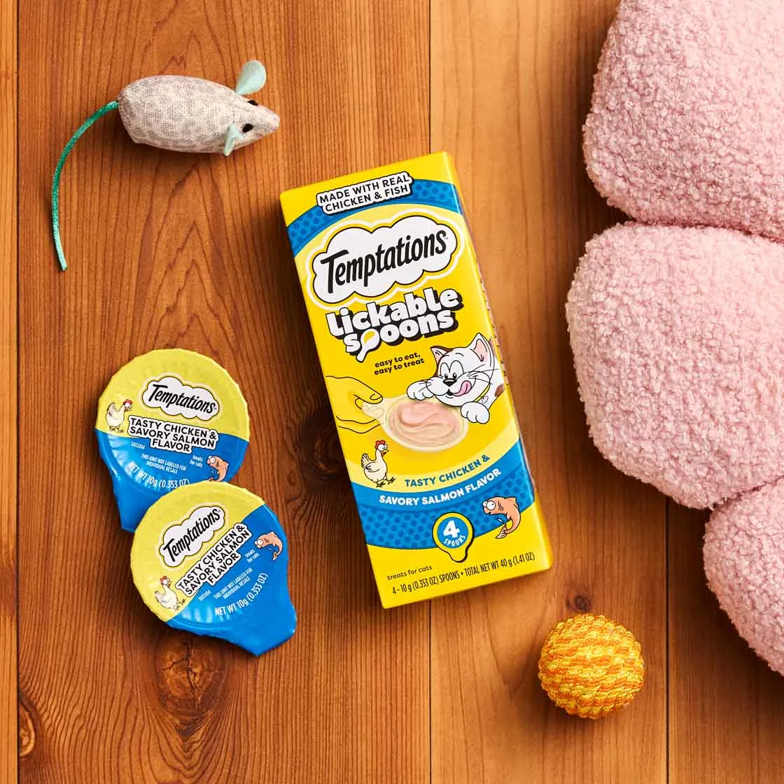 Temptations Lickable Spoons cat treats on a wooden floor with a toy mouse