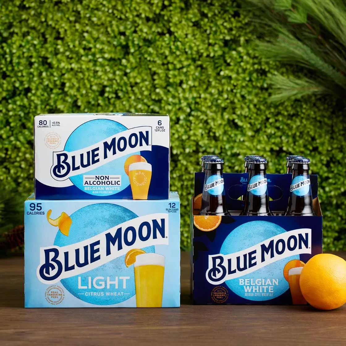 Blue Moon variety packs in front of a green hedge wall