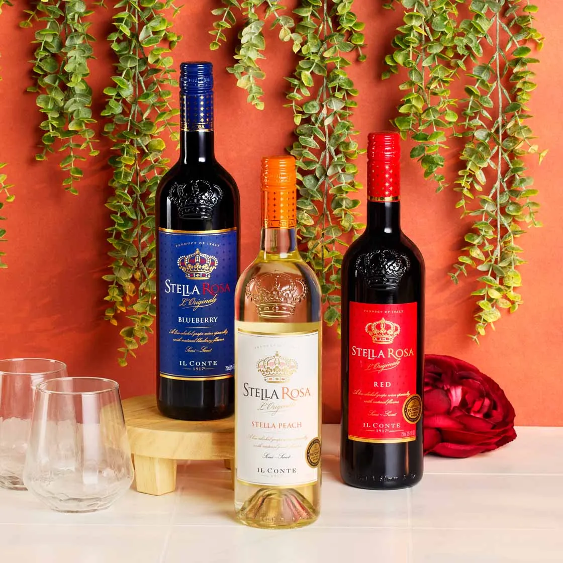 Stella Rosa wine bottles against an orange wall with hanging greenery