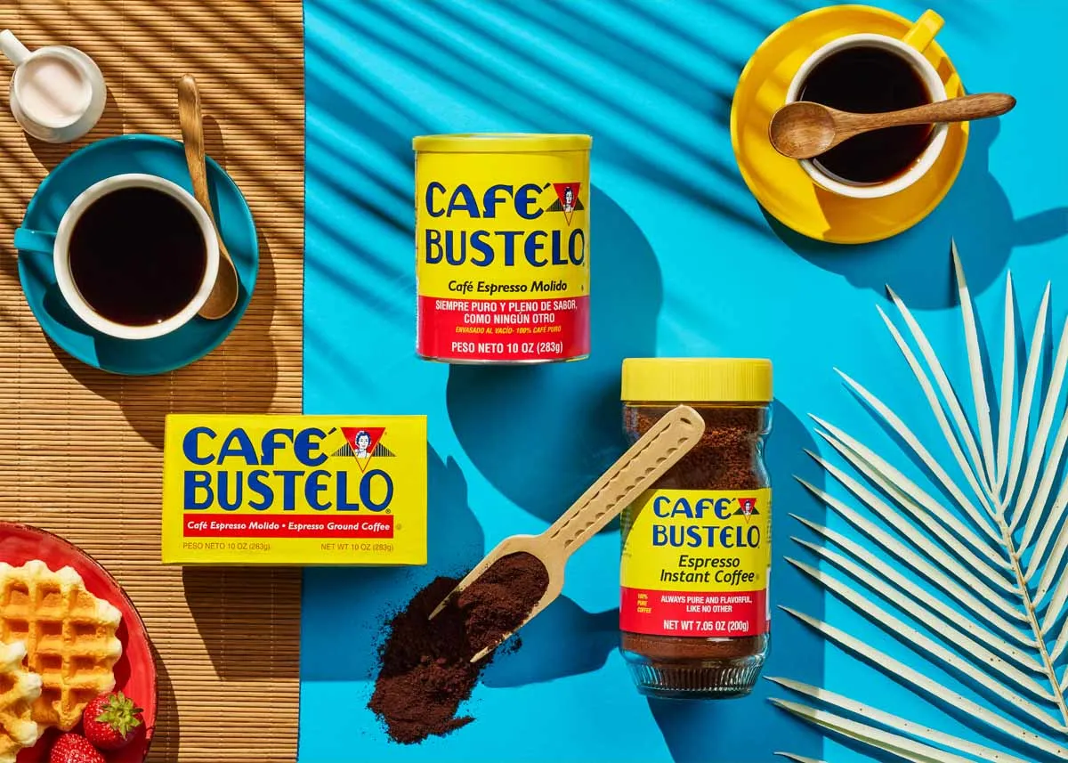 Café Bustelo coffee cans on a turquoise table with espresso cups and waffles