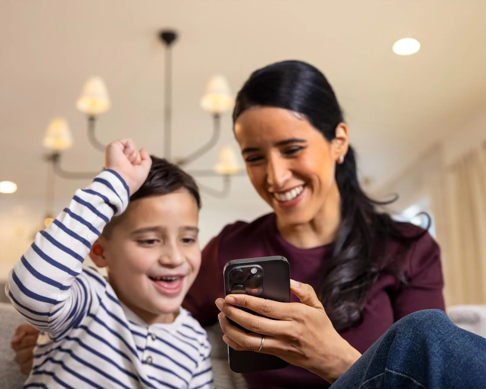 Mother and son laughing at a phone together at home