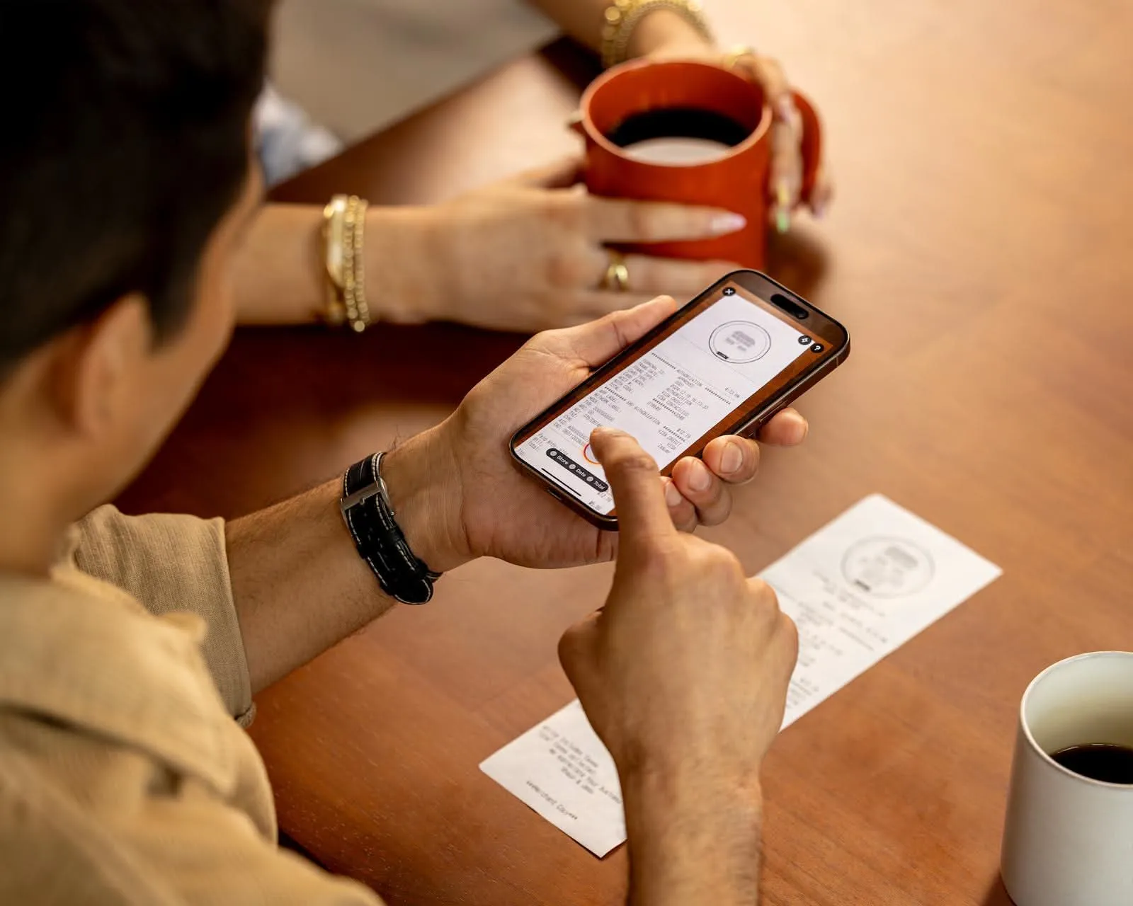 Person scanning a paper receipt with a phone at a café table