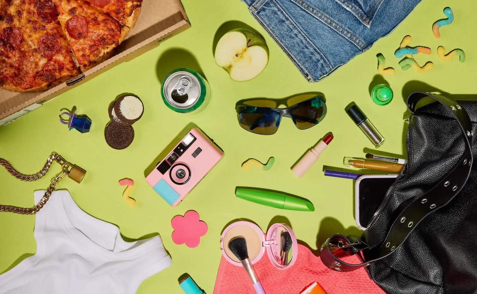 Back-to-school flat lay of clothes, snacks, and accessories on lime green