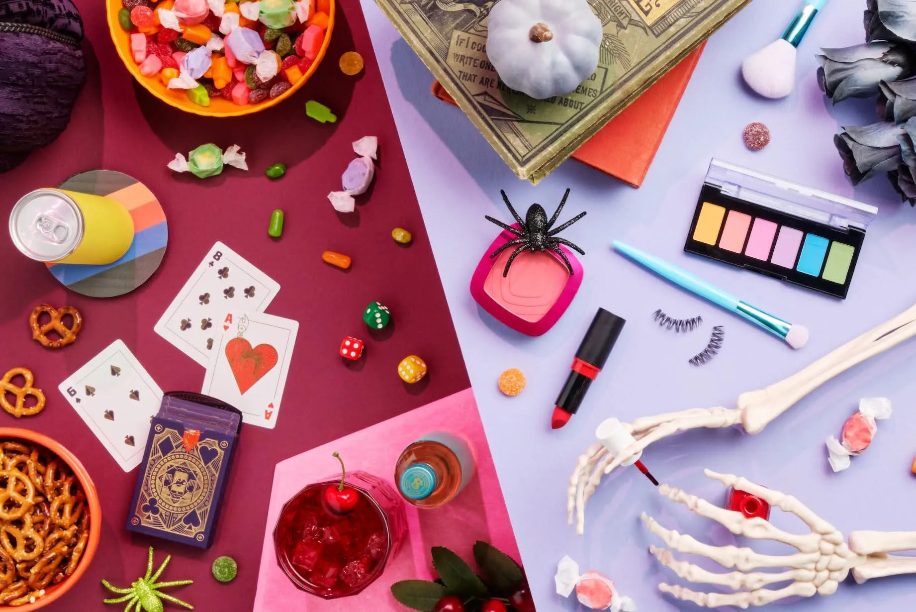 Halloween flat lay with candy, makeup, playing cards, and a skeleton hand