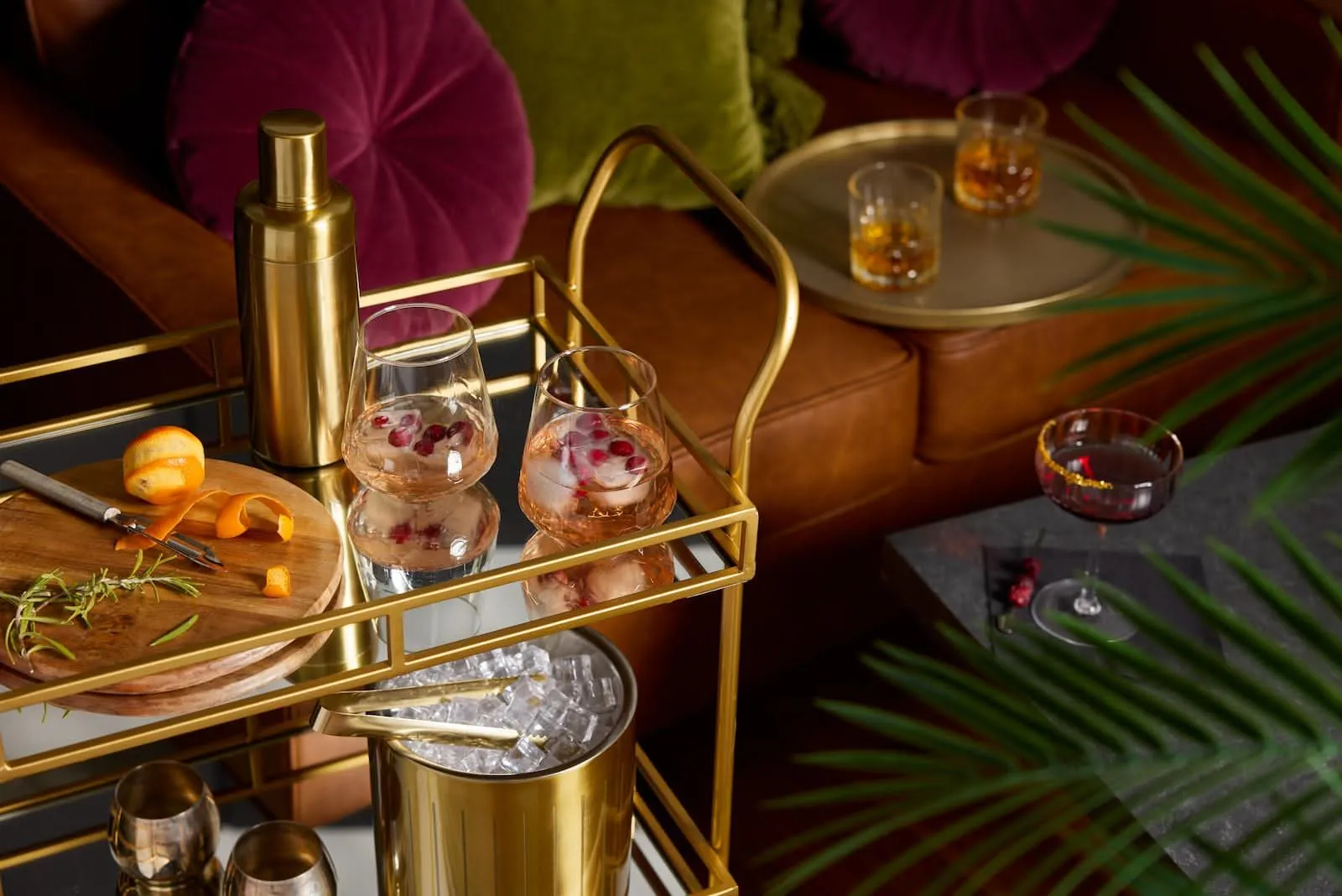 Brass bar cart with cocktail glasses and a shaker in a moody living room