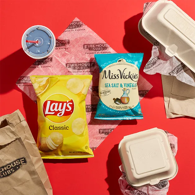 Lay's and Miss Vickie's chips with takeout containers on a red backdrop