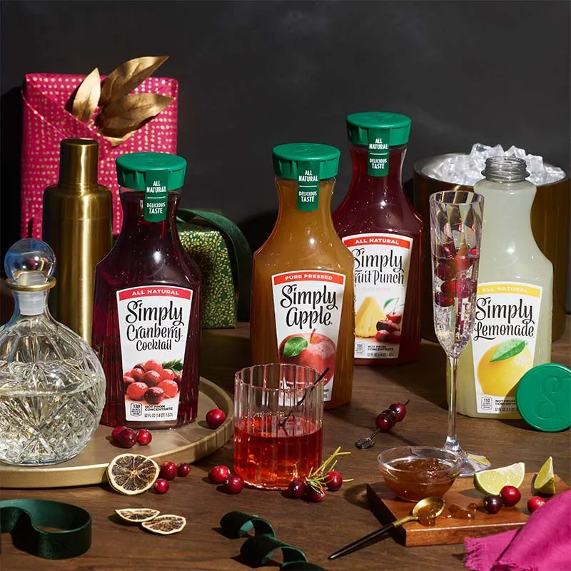 Simply juice bottles with holiday cocktails on a dark festive table