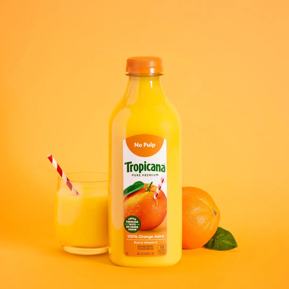 Tropicana orange juice and a glass with a striped straw on yellow