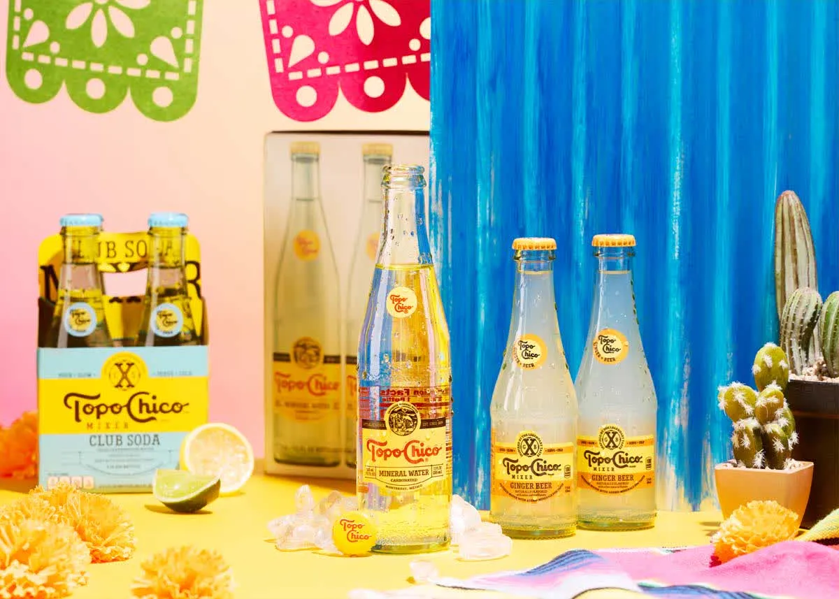 Topo Chico bottles with papel picado and cactus on a colorful set