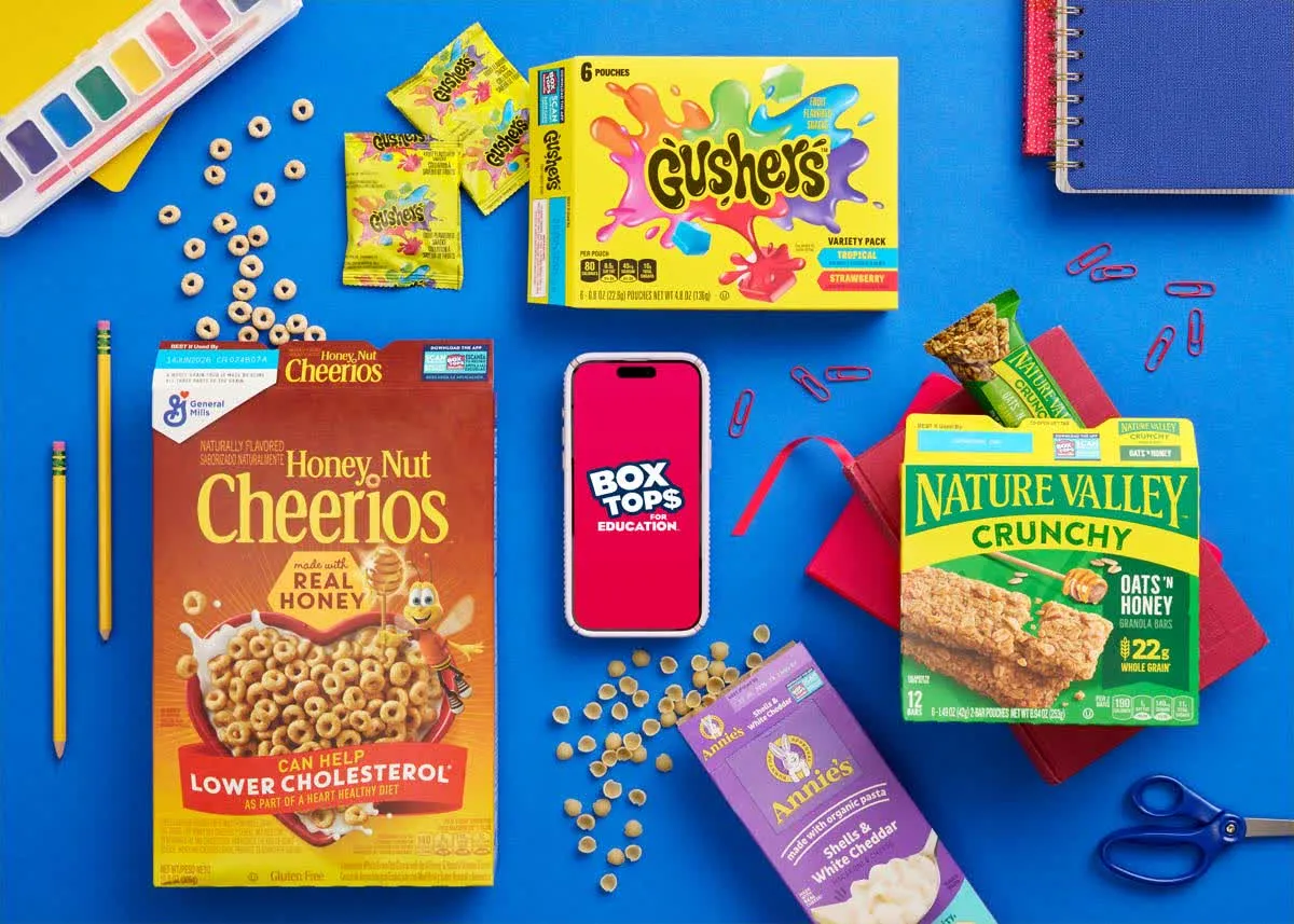 Cheerios, Gushers, and Nature Valley on a blue desk with school supplies