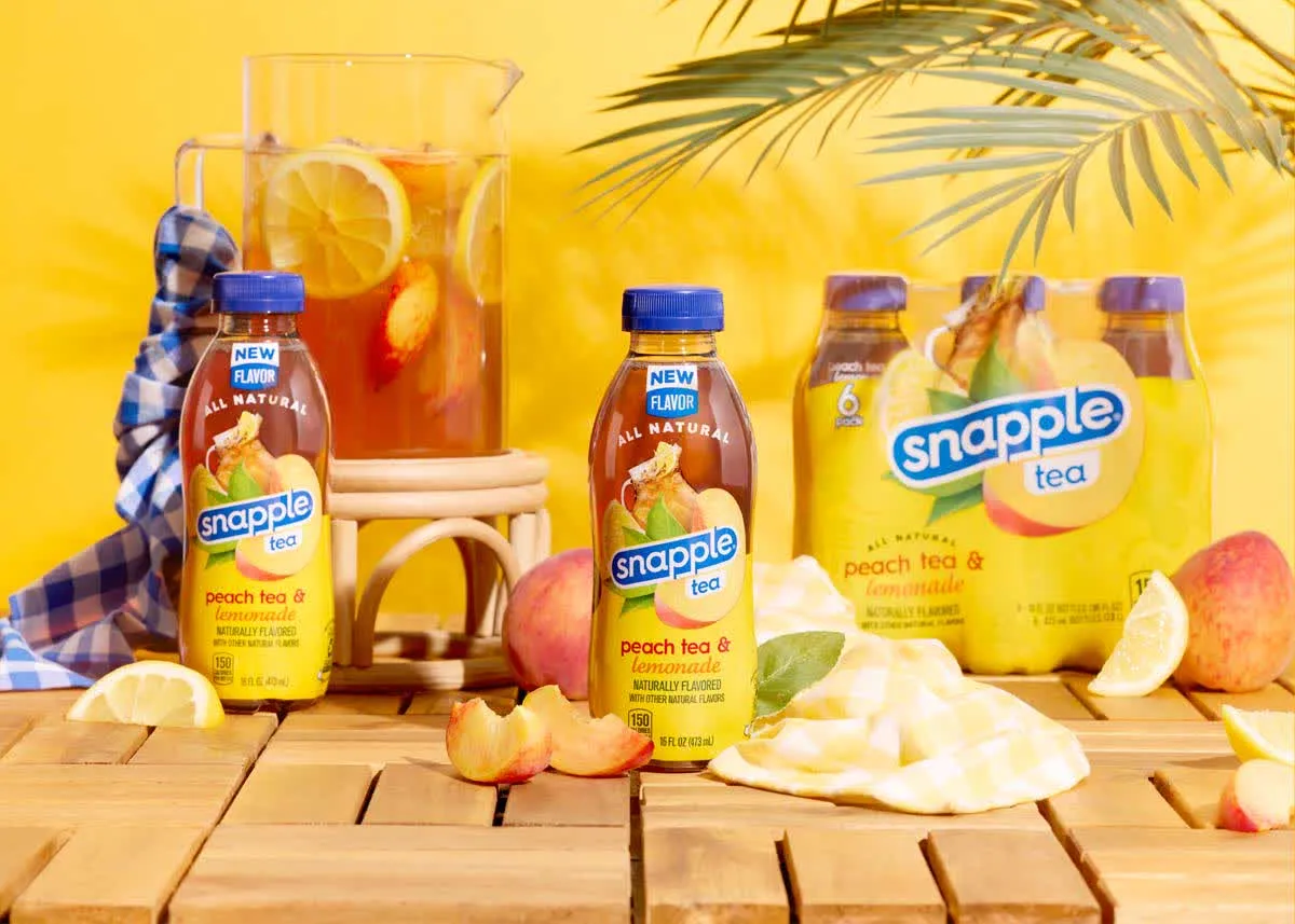 Snapple peach tea bottles on a wooden deck with lemons and peaches