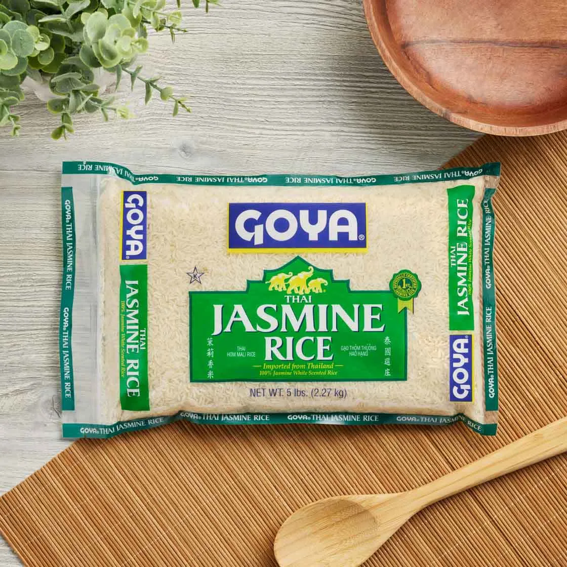 Bag of Goya jasmine rice on a wooden table with a wooden spoon