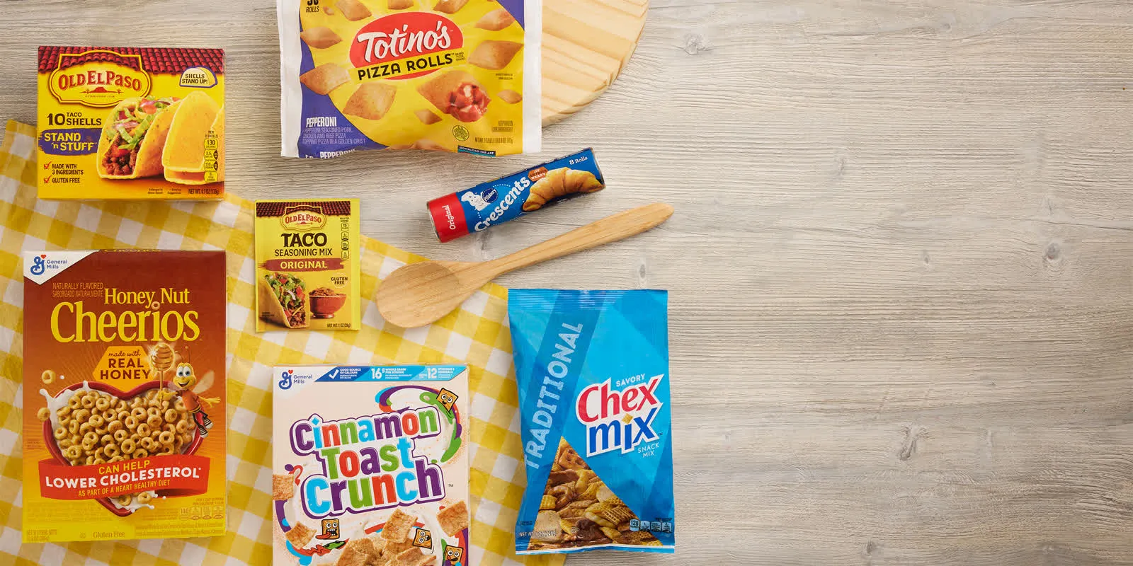 Cheerios, Totino's, and Chex Mix on a yellow cloth and wooden table