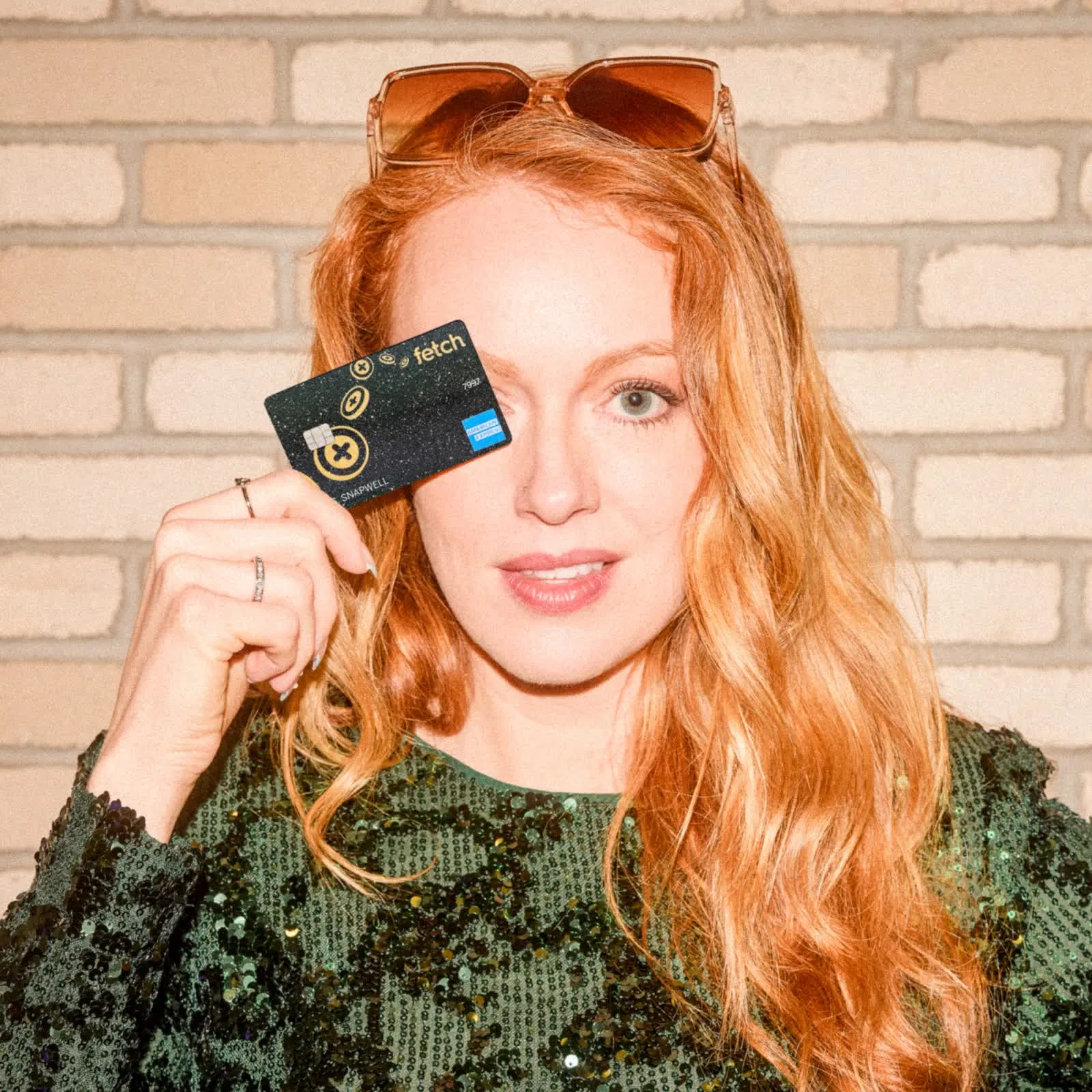 Red-haired woman holding the Fetch credit card up to her face
